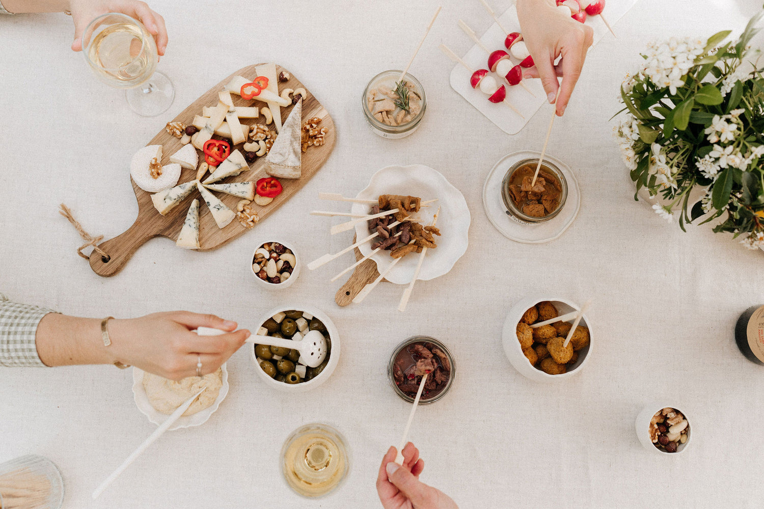 Jolie table présentant diverses tapas à piquer et autres snacks apéritifs : des olives, du fromage et les bouchées apéritives 100% végétales de Maison Hormē.